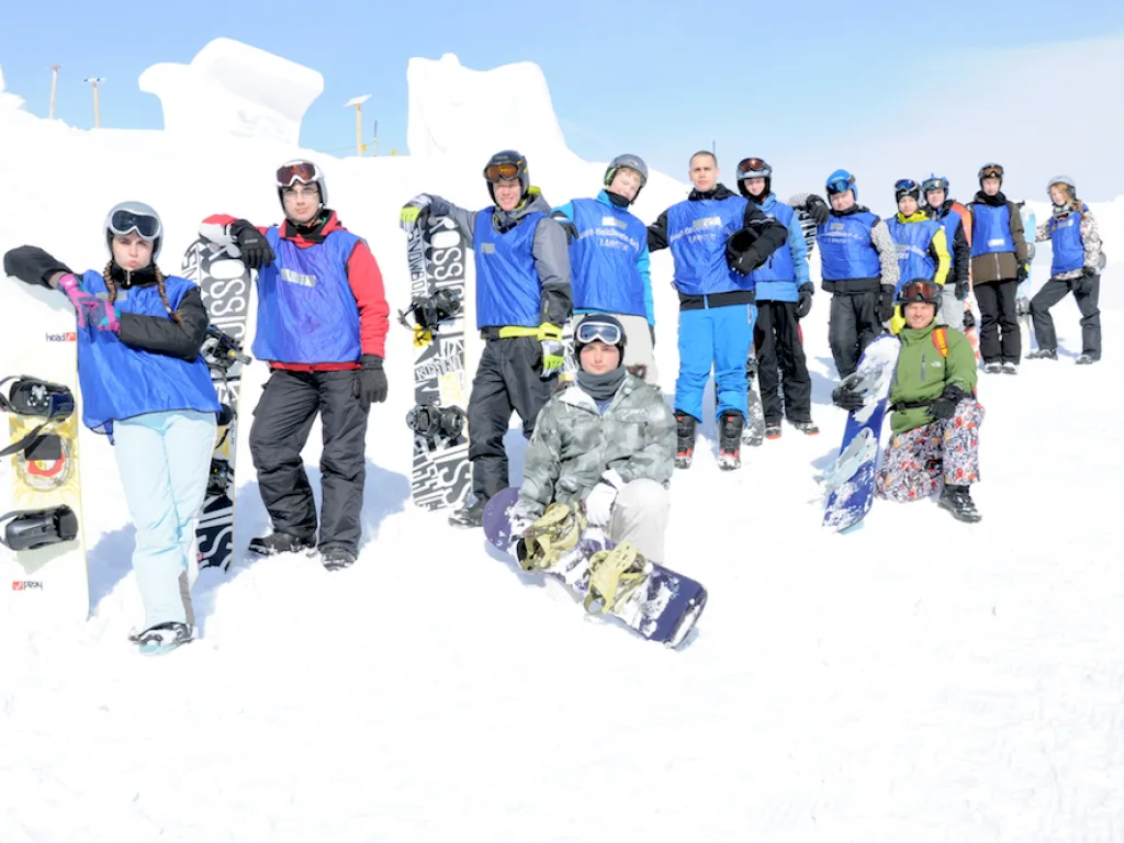 Gruppe mit Snowboards posiert im Schnee.